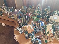 Wide view of large assortment of ceramic Christmas village buildings and accessories on a wooden table.