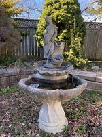 Full view of 3-piece outdoor stone/concrete garden fountain with child statue, showing the multi-tier scalloped basins and pedestal base.