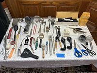 Full overview of the kitchen utensils, gadgets, knives, knife block, and scissors laid out on a white tablecloth.
