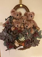 Wreath featuring five plush bears and artificial leaves with a hanging hook.