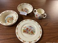Bunnykins dishes including bowl, cup, and plates on wooden table
