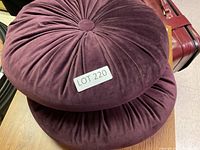 Stack of two round purple velvet cushions with ruched gathered fabric and central button, labeled LOT 220