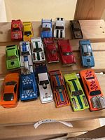 Top view of 17 die cast toy cars including bright orange, green, blue, red, white, and yellow vehicles with different decals and racing stripes.
