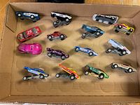 Top-down view of all 15 die cast drag racing cars in a cardboard box showing arrangement and colors