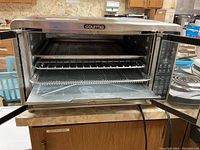 Another angle of the open air fryer oven door showing baking tray and wire racks inside.