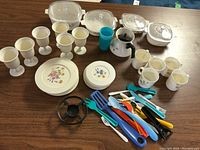 Full set of kids plastic play dishes and utensils laid on table.