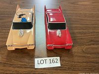 Two vintage style model cars on wooden surface with lot number card.
