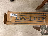 Long cardboard box labeled Da-Lite with lot number sticker, showing box condition and brand.