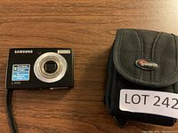 Samsung L100 digital camera alongside Lowepro carrying case on wood surface