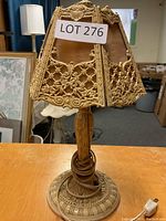 Front view of vintage table lamp showing ornate embossed metal base and textured metal lampshade with floral and scroll motifs in gold tone.