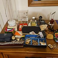 Full view of jewelry and accessories spread on dresser including boxes, coin pouch, perfumes, jewelry holders, and other small items.