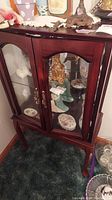Full view of the wood and glass display cabinet showing the two glass-paneled doors with brass handles and the wooden frame with dark reddish-brown stain.