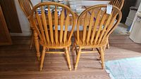 Rear view of two wooden kitchen chairs showing the slat design and condition of the wood surface.