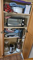 Shelf with various small kitchen appliances including toaster oven, blender, electric kettles, food processor, and small appliance covers