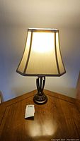 Lit table lamp showing metal base and illuminated fabric shade.