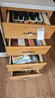 Full view of four wooden drawers holding various kitchen items including flatware, cookbooks, and kitchen linens