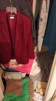 Photo showing red blazer jacket hanging among other garments.