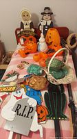 Overview photo showing pilgrim couple wooden decorations, orange jack-o-lantern blow molds, white rabbit blow mold, woven baskets, and part of the black cat wooden decoration on bed