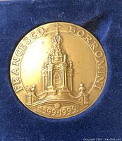 Close-up of bronze medallion showing detailed architectural relief and inscriptions.