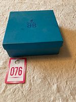 Blue Birks jewelry box closed on beige fabric.