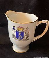 Front view of Royal Grafton creamer with Halifax coat of arms and gold trim around rim and handle.