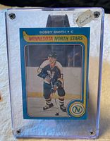 Front side of the Bobby Smith rookie card in a protective case with a handwritten 'Rookie' tag.