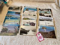 Initial overview photo of multiple stacks of vintage postcards arranged side by side on a white surface.