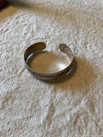 Vintage sterling silver child bracelet displayed on a cloth background showing the cuff style and engraved pattern.