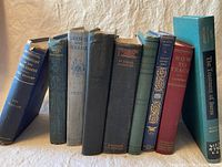 Photo of 9 vintage books arranged standing showing title on spine.