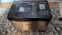 Full front view of the bread maker showing stainless steel body and Black+Decker branding.