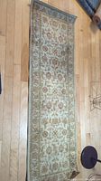 Full length view of floral carpet runner on wood floor showing its overall size and pattern.