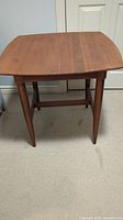 Front view showing the square top and tapered legs of the cherry wood table.