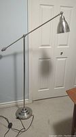 Full view of adjustable floor lamp showing long arm, round base, and cord with floor switch.