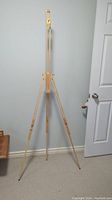 Easel fully extended, standing upright showing three legs and central adjustable frame.