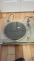 Full top view of Pioneer PL-300 turntable with dust cover and attached RCA cables on wood flooring.