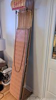 Full view of the vintage Sno-Jet wooden sled toboggan showing the woven seat, wooden slatted backrest with curved top, and rope attached for pulling.