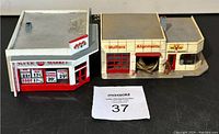 Front and angled view of both HO scale buildings, supermarket on the left and Victory Service garage on the right, showing signage and storefront details.