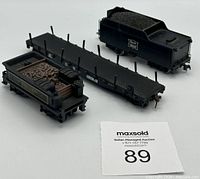 Three black HO scale model train cars displayed together: a coal tender with 'Rock Island' logo, flatbed car, and open hopper car with molded cargo.