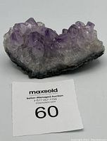 Amethyst cluster with purple pointed crystals on dark matrix base alongside auction card with lot #60.
