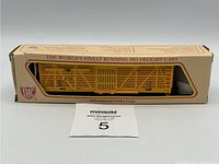Photo of the boxed IHC HO scale yellow 40 stock car showing original packaging and model visible through window.