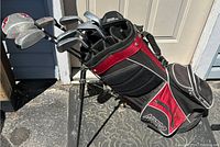 Full view of the Nitro golf bag loaded with left handed golf clubs standing outside on a doormat.