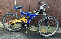 Full side view of blue and yellow SuperCycle Hooligan mountain bike showing frame, tires, pedals, and suspension.