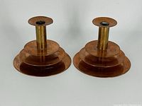 Pair of copper modernist candle holders side by side showing the tiered circular base design and cylindrical candle socket.