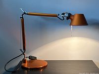 Front three-quarter view of lamp on table showing full adjustable arm and shade.