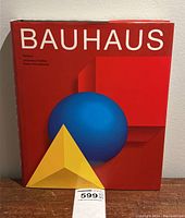 Front cover of the book showing the red background with geometric shapes (cube, sphere, pyramid) and title 'BAUHAUS'.