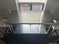 Front view of stainless steel table showing top surface and lower shelf under a window