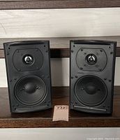 Pair of Definitive Technology ProMonitor 100 ProCinema speakers front view without grill showing tweeter and mid/bass drivers on each speaker.