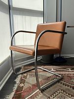 Front three-quarter view of a single chair showing chrome cantilever frame and caramel leather upholstery