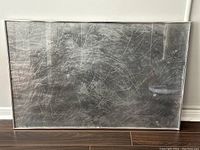 Front view of framed painting showing abstract silver-gray surface with white scribbles