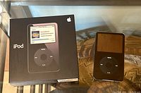 Apple iPod Video 5th generation with black color, displaying front click wheel and partial screen shown. Original box included beside it.